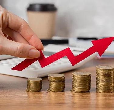 Crescimento financeiro representado por pilhas de moedas e seta ascendente indicando evolução patrimonial